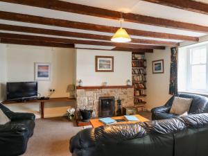 een woonkamer met lederen meubels en een open haard bij Cherry Tree Cottage in Embleton