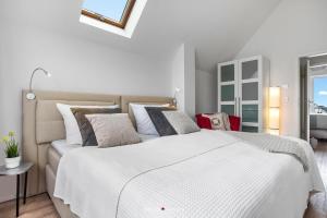 a white bedroom with a large white bed with pillows at Ferienwohnung Santiano Lounge in Olpenitz
