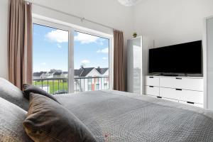 a bedroom with a large window and a television at Ferienwohnung Santiano Lounge in Olpenitz