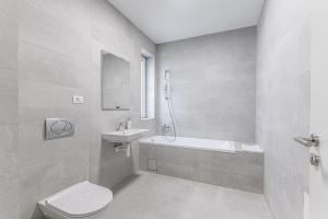 a white bathroom with a toilet and a sink at KOA - Fidelio Apartments in Braşov