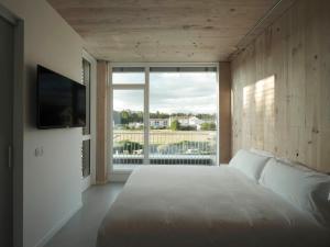 a bedroom with a white bed and a large window at Hotel Amiuka in O Pedrouzo