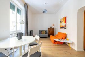een woonkamer met een witte tafel en een oranje bank bij Urban Chic 2 BR Vatican Escape in Rome