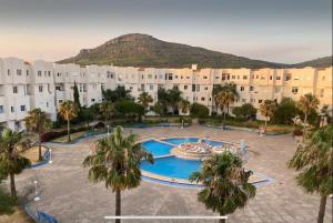 an apartment complex with a swimming pool and palm trees at Duplex Deluxe Arous Al Bahr in Tangier