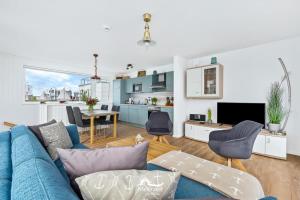 sala de estar con sofá azul y cocina en 5 Beaufort - Wasserhaus, Meerblick, Sauna, Dachterrasse, Bootsanleger, Strandkorb en Olpenitz