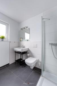 a white bathroom with a sink and a toilet at Wasserhaus Klabautermann in Olpenitz