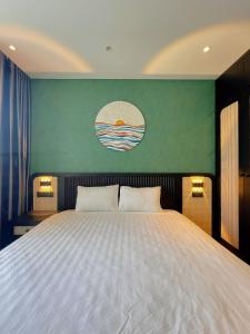 a bedroom with a large white bed with a green wall at Tony Apartment - Apec Mandala Phú Yên in Tuy Hoa