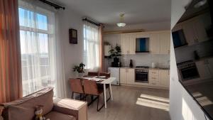 a kitchen with white cabinets and a table and a couch at Assalom Apartment 6 in Tashkent