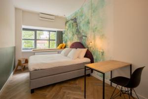 1 dormitorio con cama, mesa y ventana en Badhuis Hotel en Utrecht