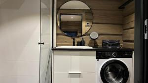 ein Badezimmer mit einer Waschmaschine und einem Spiegel in der Unterkunft Invisible Forest Lodge in Rovaniemi