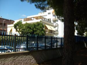 una cerca frente a un edificio blanco con un árbol en B&B Il Parco, en Civitavecchia