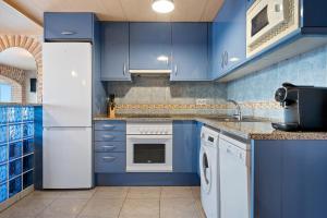 cocina azul con nevera y lavavajillas en Hauzify I Apartament Plenamar, en Platja d'Aro
