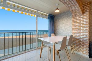 un comedor con mesa y sillas y el océano en Hauzify I Apartament Plenamar, en Platja d'Aro