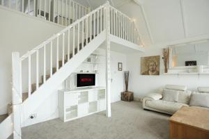 uma sala de estar branca com uma escada e um sofá em Secret Seaside Retreat em Kent