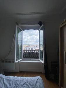 een slaapkamer met een groot raam met uitzicht bij Appartement vue sur Tour Eiffel à 5 min de Paris in Issy-les-Moulineaux