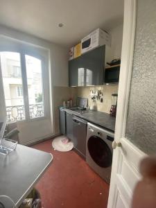 een keuken met een wasmachine en een raam bij Appartement vue sur Tour Eiffel à 5 min de Paris in Issy-les-Moulineaux