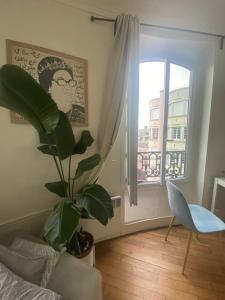 een woonkamer met een plant en een raam bij Appartement vue sur Tour Eiffel à 5 min de Paris in Issy-les-Moulineaux