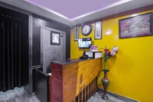 una habitación con una pared amarilla y un jarrón con flores en Club House Guest House,Bhubaneswar, en Bhubaneshwar