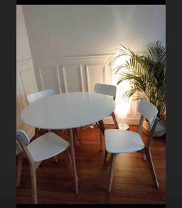 een witte tafel en stoelen in een kamer met een plant bij Appartement vue sur Tour Eiffel à 5 min de Paris in Issy-les-Moulineaux