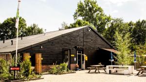 ein schwarzes Gebäude mit einem Picknicktisch davor in der Unterkunft Vakantiepark de Toffe Peer in Ruinerwold