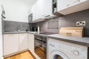 a kitchen with white cabinets and a washer and dryer at The Botanical Flat 1 in Sheffield