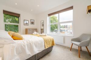 a bedroom with a bed and a chair and windows at The Botanical Flat 1 in Sheffield