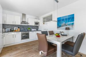 une cuisine avec des placards blancs et une table et des chaises blanches dans l'établissement Ferienwohnung Kap Mar, à Olpenitz