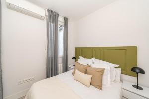 馬德里的住宿－Premium Apartment LaLatina II Renovated 3BR 3BH，一间卧室配有一张带绿色床头板和枕头的床。