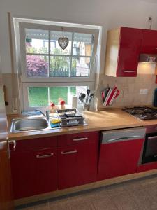 a kitchen with red cabinets and a sink and a window at Ferienhaus Glückspilz beim Hennesee in Meschede