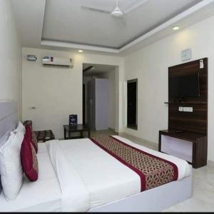 a bedroom with a large white bed and a television at Laxmi Stay Hotel in New Delhi