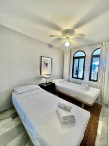 two beds in a room with two windows at Apartamento En Pueblo Evita Con Piscina Y Terraza in Benalmadena Costa
