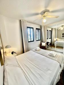 1 dormitorio con 1 cama blanca grande y espejo en Apartamento En Pueblo Evita Con Piscina Y Terraza en Benalmadena Costa