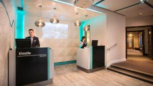 a man and a woman standing at a counter with a laptop at Thistle London Piccadilly in London