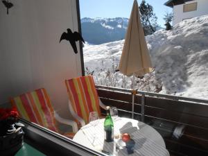 stół i krzesła na balkonie z pokrytą śniegiem górą w obiekcie Ferienwohnung Roland w mieście Balderschwang