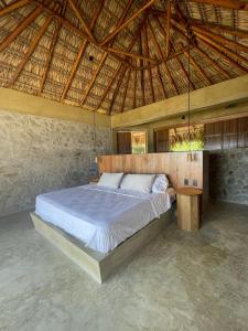 Utopia Beach House & Suites في Santa María Tonameca: غرفة نوم بسرير كبير بسقف خشبي