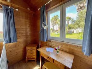 a desk in a wooden room with two windows at Da Silva Surfcamp - Tiny House Jorgina in Lourinhã