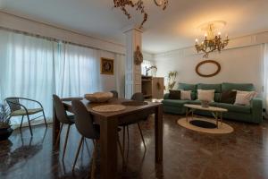 a living room with a table and a green couch at Ático Puente Romano PARKING GRATUITO in Córdoba