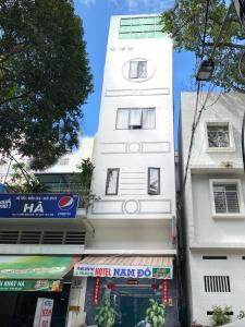 a tall white building with a shop in front of it at Khách Sạn Nam Đô 1 in Can Tho