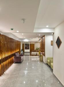 een lobby met een bank en stoelen in een gebouw bij The Habitat Suites in Guruvāyūr