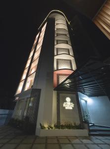 a tall building with a sign on it at night at The Habitat Suites in Guruvāyūr