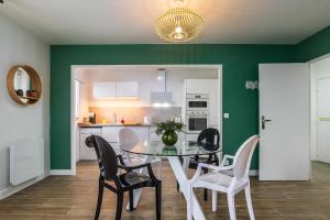 a dining room with green walls and a table and chairs at Lémeraude Magic Dreams Near Disneyland in Montévrain