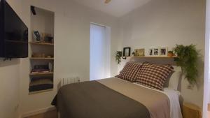een slaapkamer met een bed en een flatscreen-tv bij RentAdore Atocha Suites in Madrid