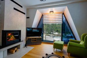 a living room with a fireplace and a large window at Winter House TT Jahorina in Jahorina