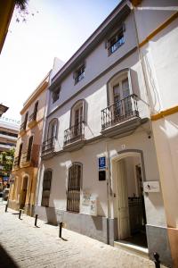 a white building with balconies on a street at Hostal San Francisco in Seville