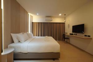 a bedroom with a bed and a desk and a television at Alto Hotel M in Mae Sot