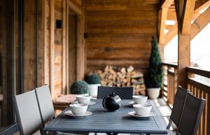 a black table with cups and chairs on a porch at A brand new apartment in a calm environment in Praz-sur-Arly