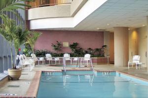 - une piscine dans un hôtel avec des tables et des chaises blanches dans l'établissement Embassy Suites by Hilton Bethesda Washington DC, à Bethesda