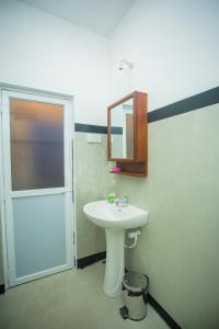 a bathroom with a sink and a mirror and a door at Villa Kavee in Galle