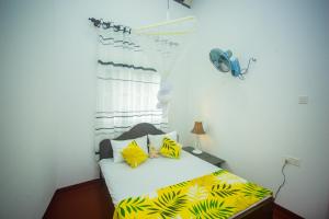 a bedroom with a bed with yellow and black pillows at Villa Kavee in Galle