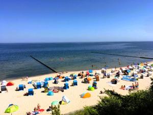un grupo de personas en una playa con sombrillas en Beim Windmüller App 2,3,4,5, en Ostseebad Koserow 45 fotos más