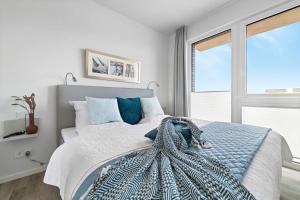 een witte slaapkamer met een groot bed met blauwe kussens bij BeachTerraceOne - EG, Meerblick, Terrasse, Kamin, Sauna in Olpenitz